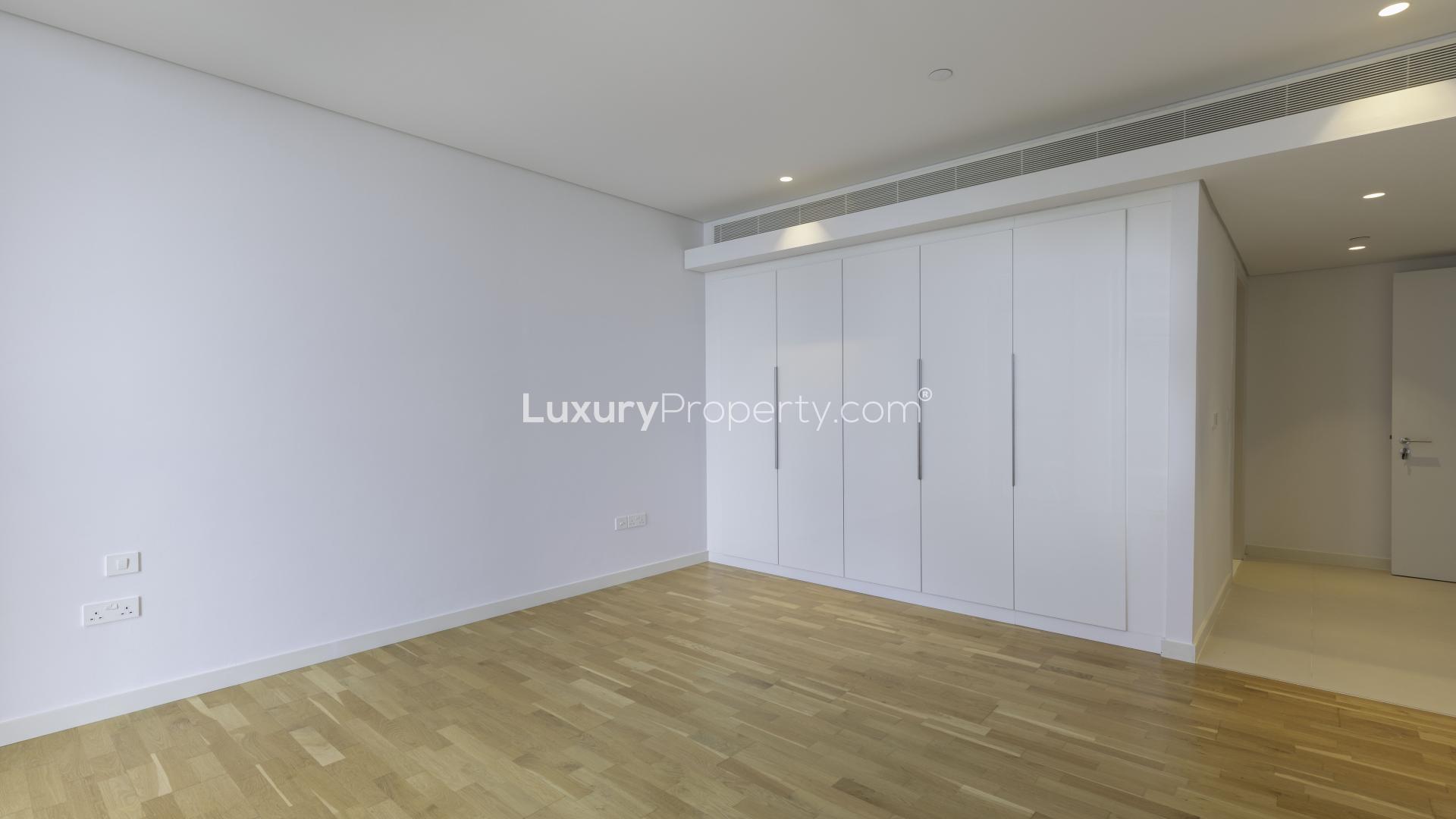 Empty bedroom with wooden floors and built-in wardrobe at Bluewaters Residences apartment
