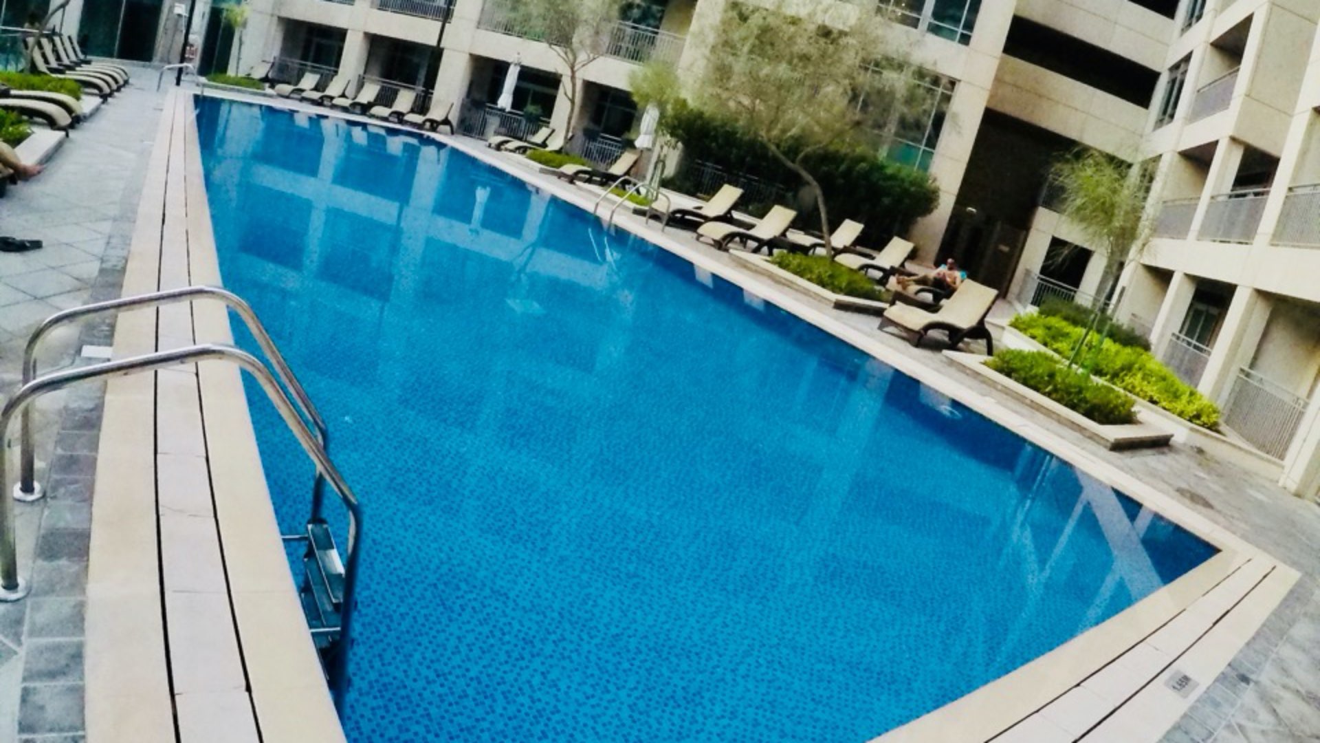 Outdoor swimming pool at Burj Views apartment complex, Downtown Dubai, surrounded by palm trees