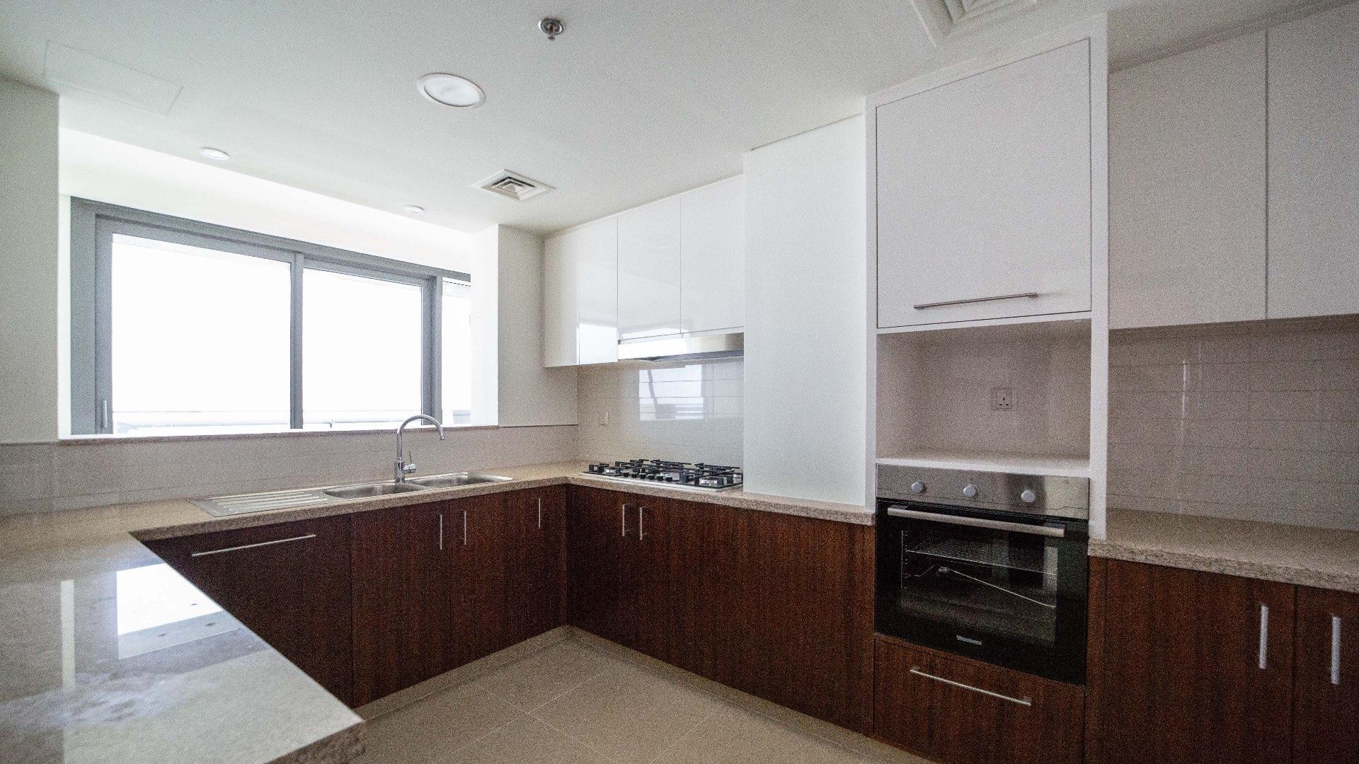 Modern kitchen in Burj Vista apartment, Downtown Dubai, with sleek cabinets and large window