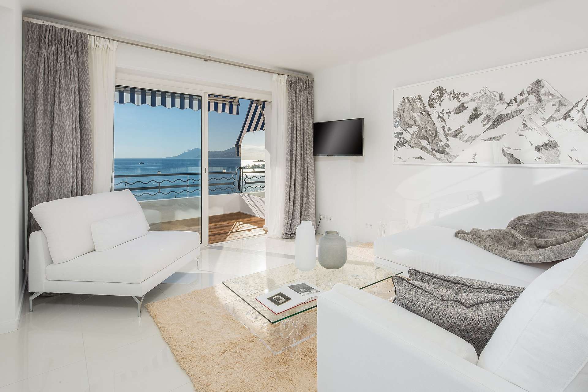 Stylish living room in 2-bedroom Cannes apartment, featuring modern decor and glass table