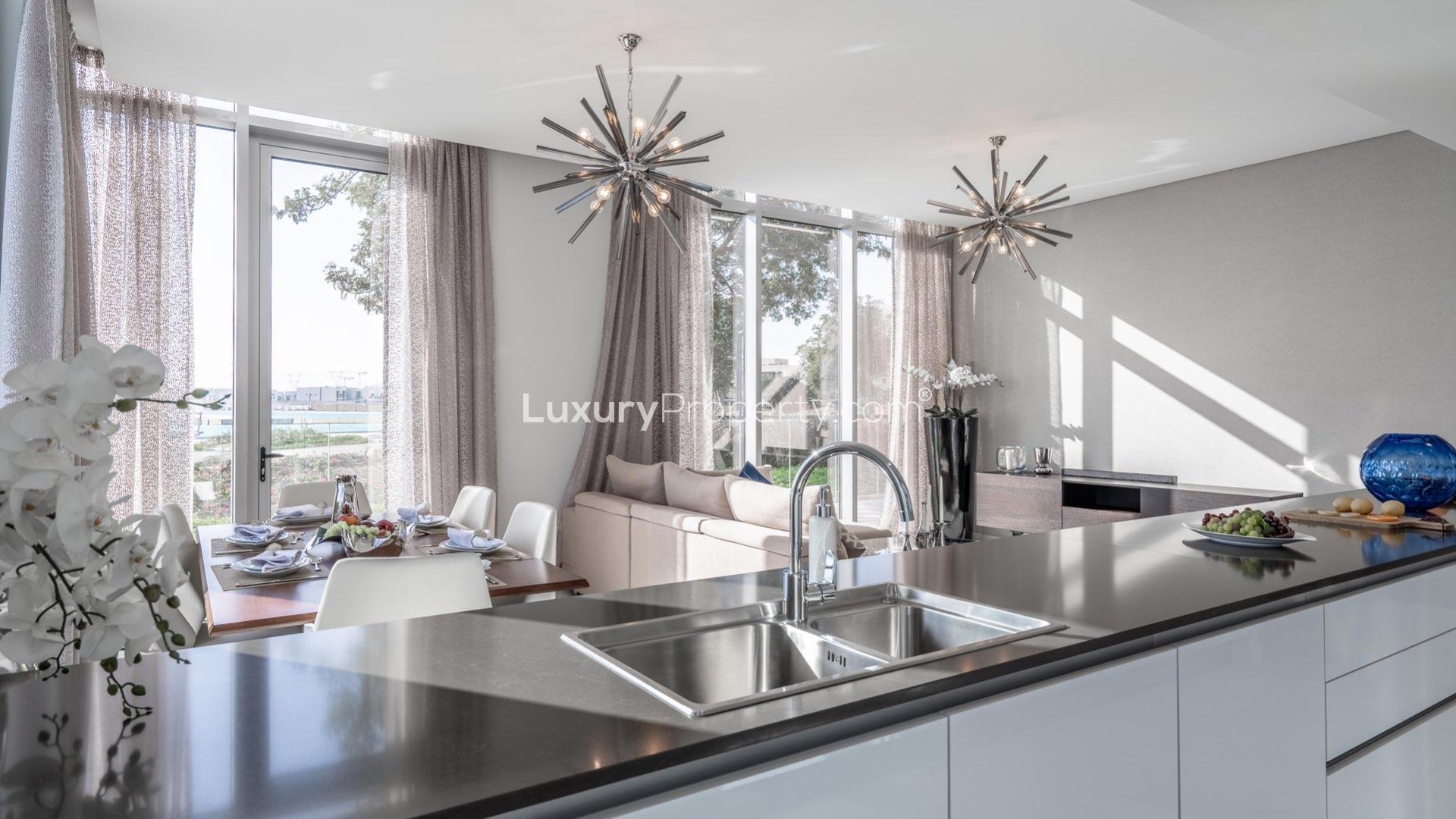 Furnished living room with large windows in lagoon-facing apartment, District One, MBR City