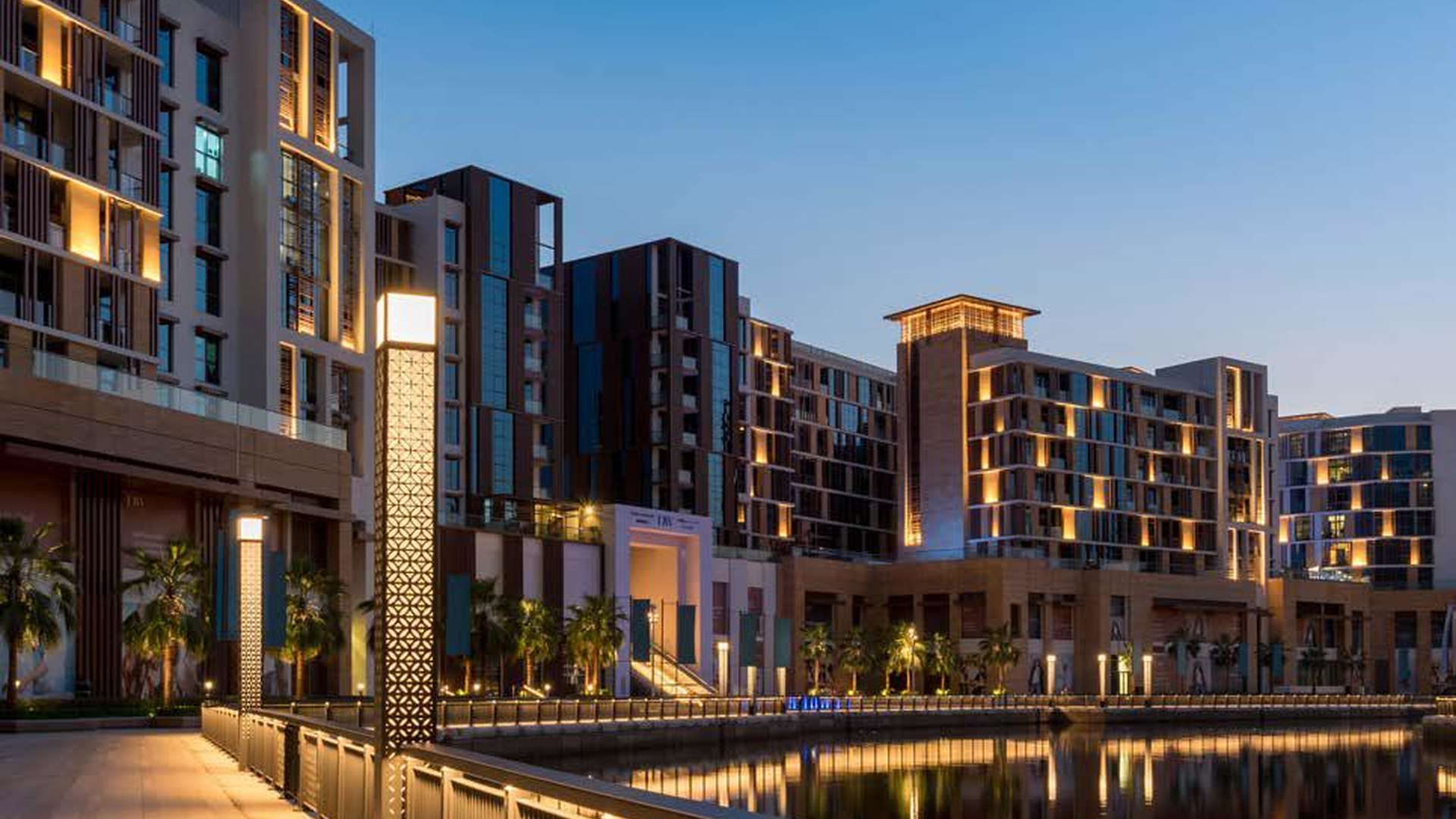 Modern kitchen in two-bedroom Dubai Wharf apartment, featuring granite countertops and mosaic backsplash