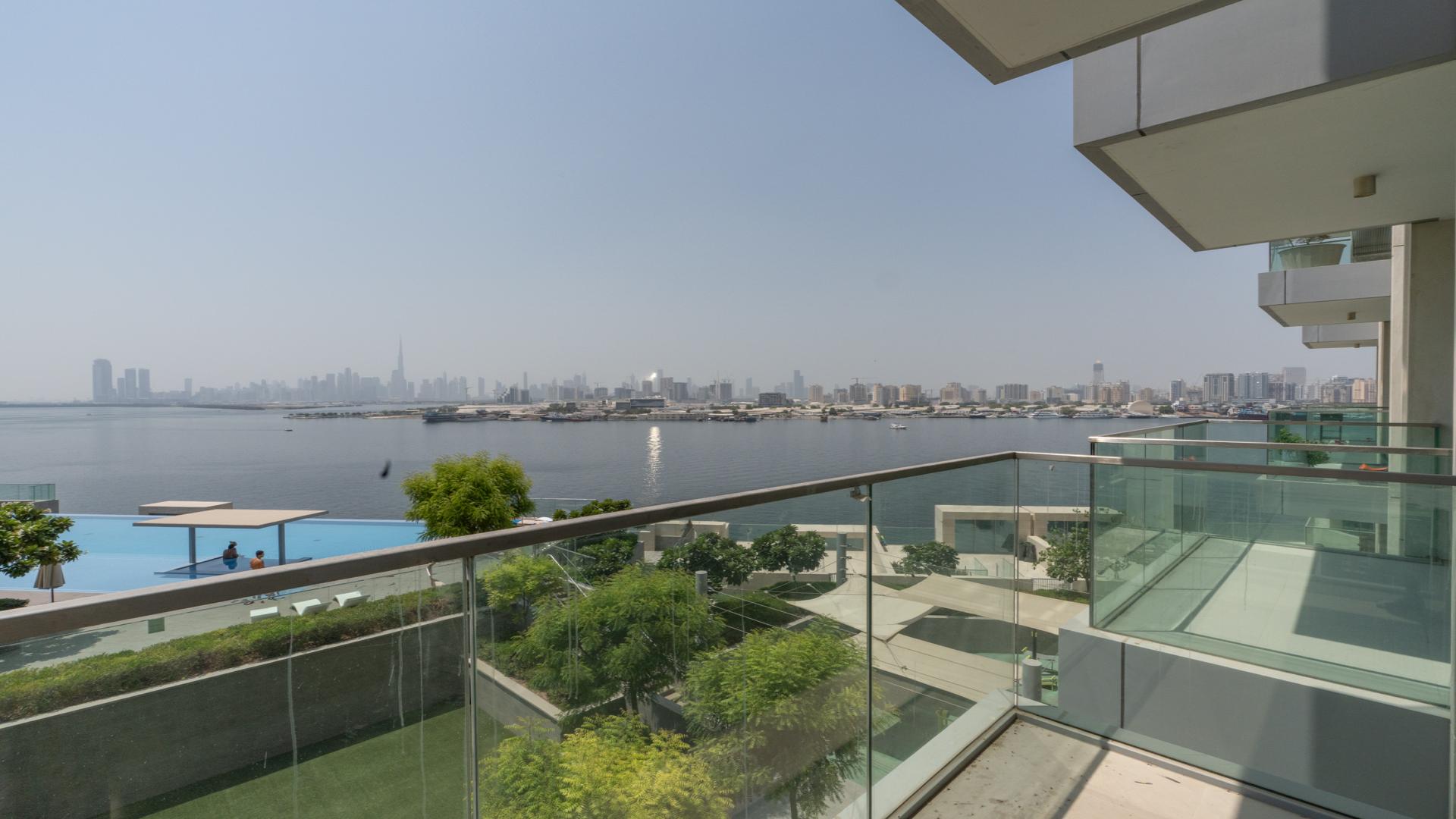 Modern living room in The Grand apartment, Dubai Creek Harbour, featuring balcony with waterfront view