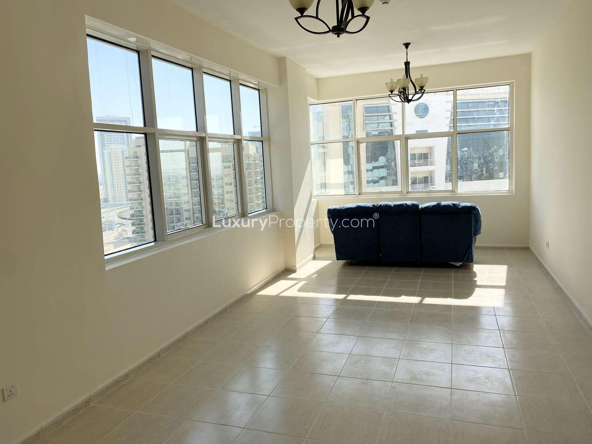 Spacious living room with large windows in Olympic Tower 2, Dubai Sports City apartment