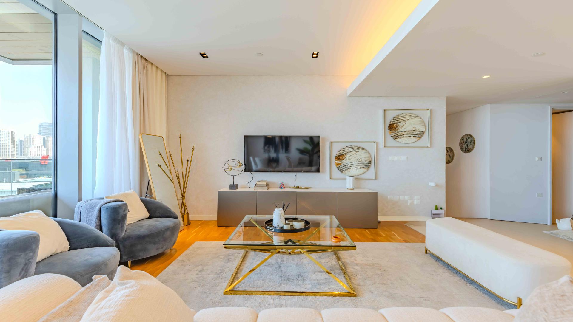 Furnished living room in sea-facing Bluewaters apartment with modern decor and large windows