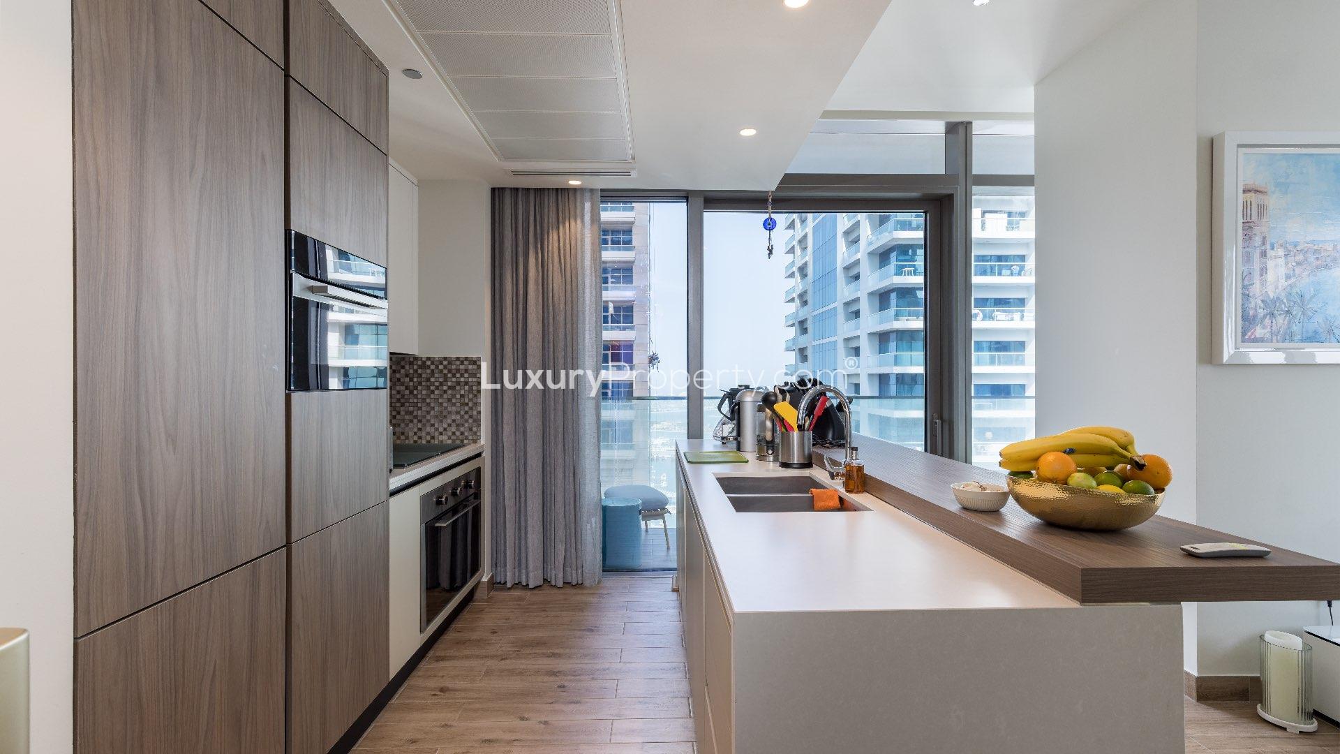 Modern kitchen in upgraded Jumeirah Living Marina Gate apartment, Dubai Marina, with balcony view