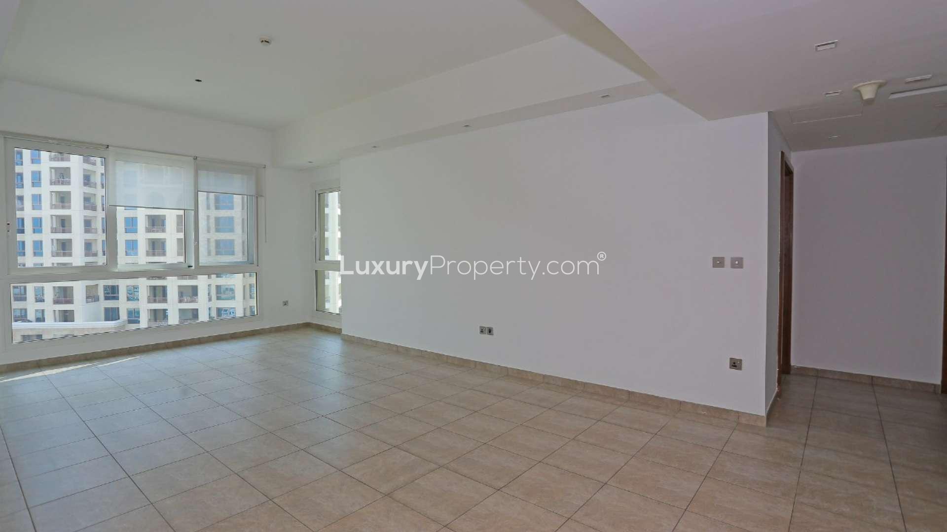 Empty living room in Marina Residence apartment with large windows and tiled floor