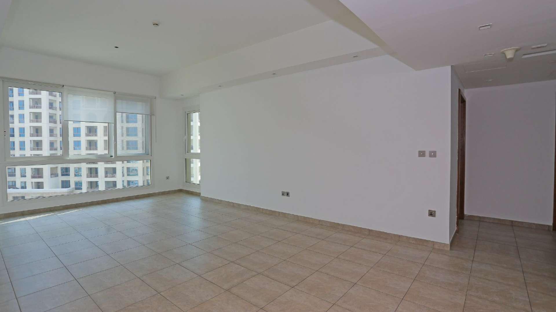 Empty living room in Marina Residence apartment with large windows and tiled floor