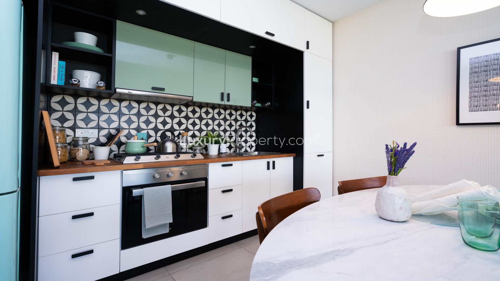 Modern kitchen in Dubai Hills Estate apartment, featuring stylish cabinets and patterned backsplash