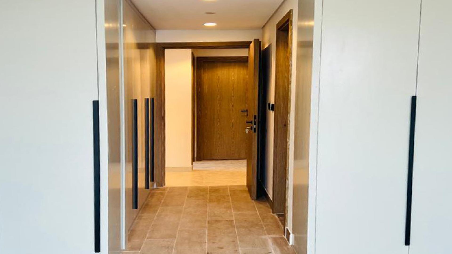Hallway with large window and built-in wardrobes in Golf Gate apartment, Damac Hills