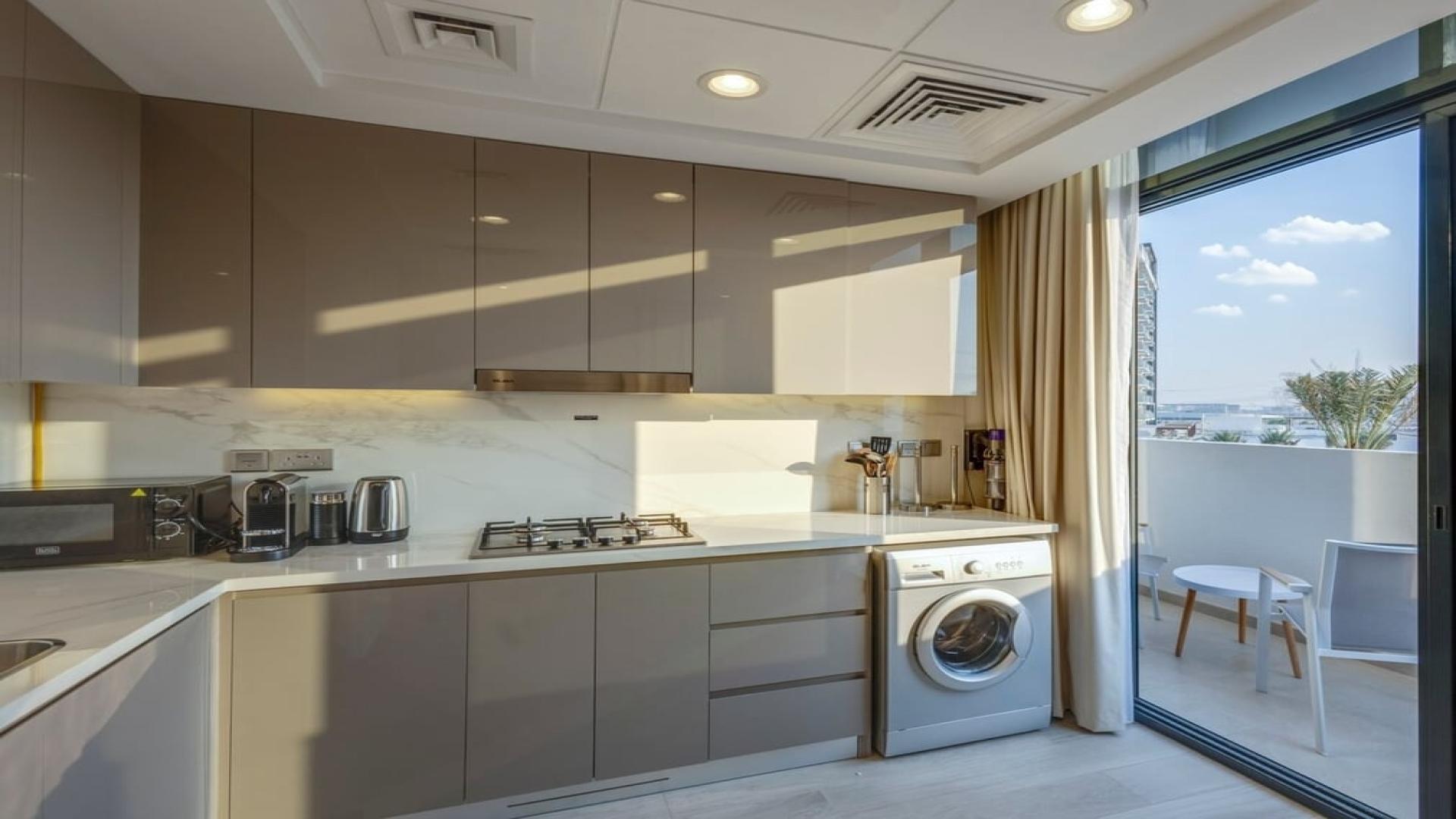 Elegant dining area in Meydan One apartment, featuring blue chairs and glass table