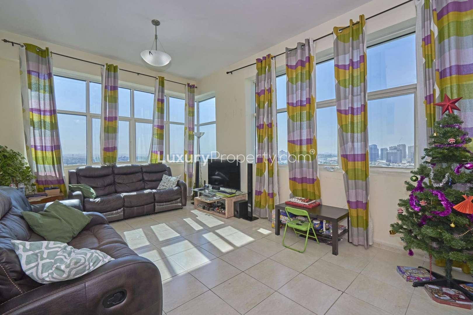 "Exterior view of Olympic Tower 1 apartment in Dubai Sports City for sale.",Living room in 2-bedroom apartment, Olympic Tower 1, with golf course views, Dubai Sports City