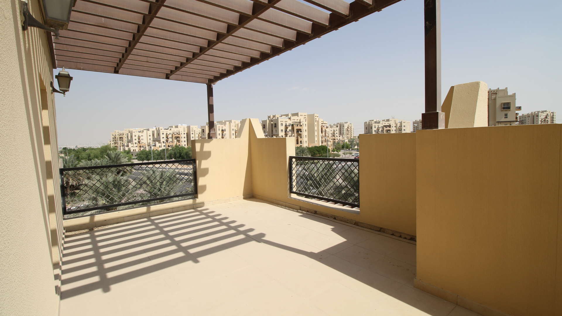 Empty room with large windows, tiled floor, and balcony view in Remraam apartment