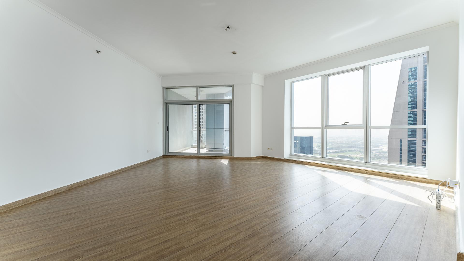 "Spacious living area with large windows, high floor apartment in Torch Tower, Dubai Marina.",Vacant high-floor apartment with large windows and wooden floors in Torch Tower, Dubai Marina