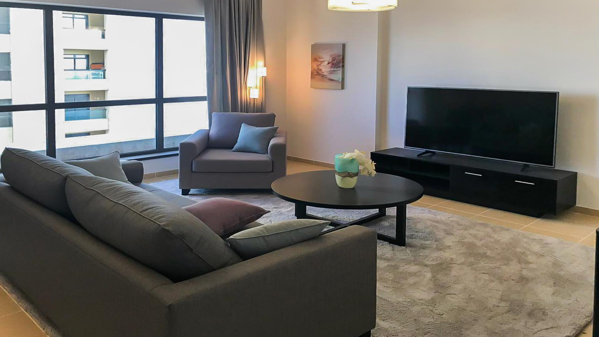 Living room in semi-upgraded JBR apartment, modern decor, dining area, sea views