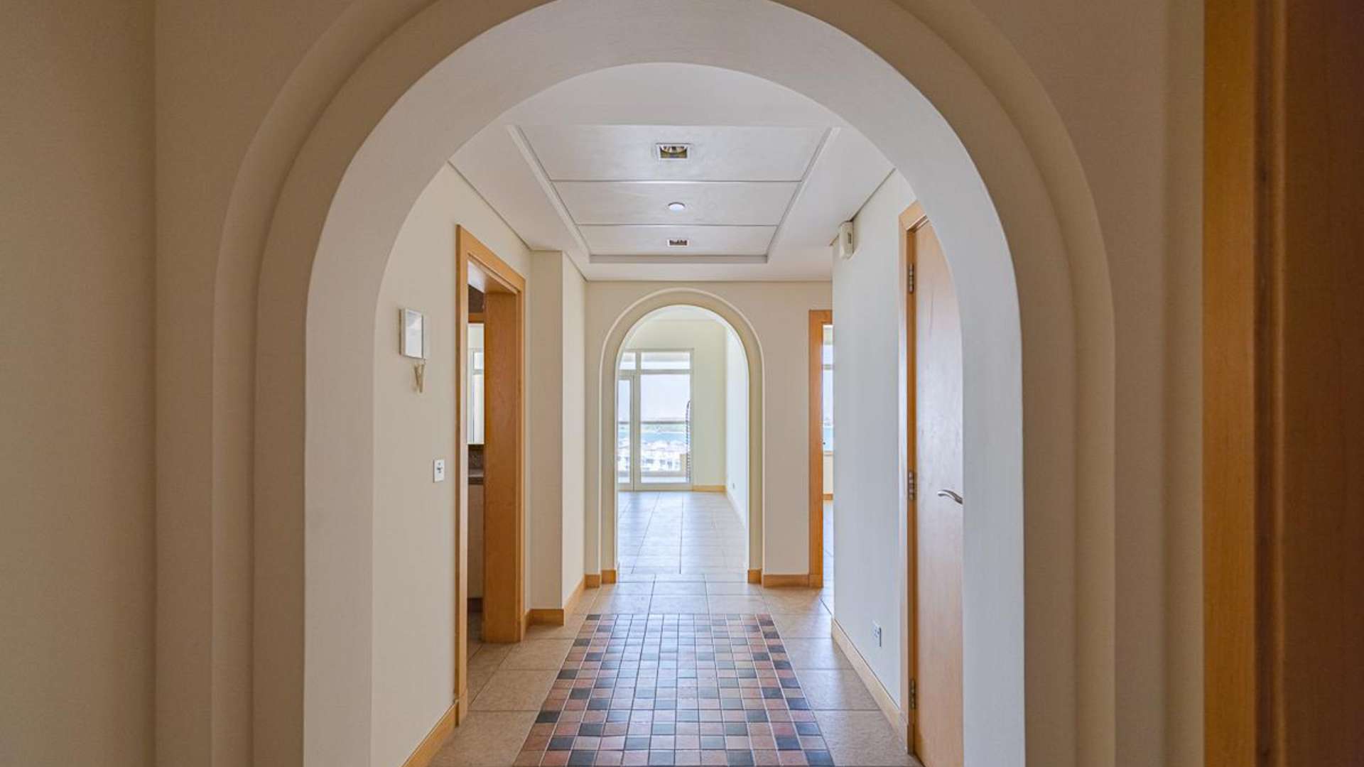 Empty room in Shoreline Apartments, Palm Jumeirah, featuring wooden doors and tiled flooring