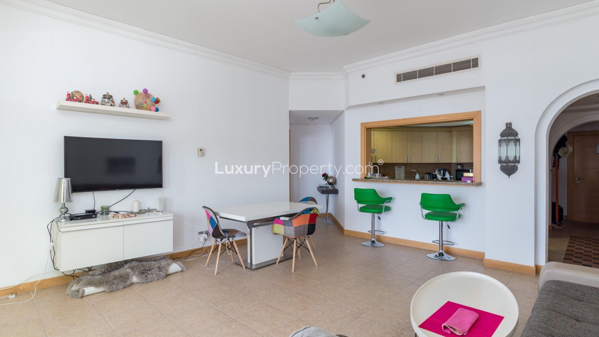 "Modern kitchen in Palm Jumeirah apartment with granite countertops and sea view window.",Modern living room in Shoreline Apartments, Palm Jumeirah, with open kitchen and colorful chairs