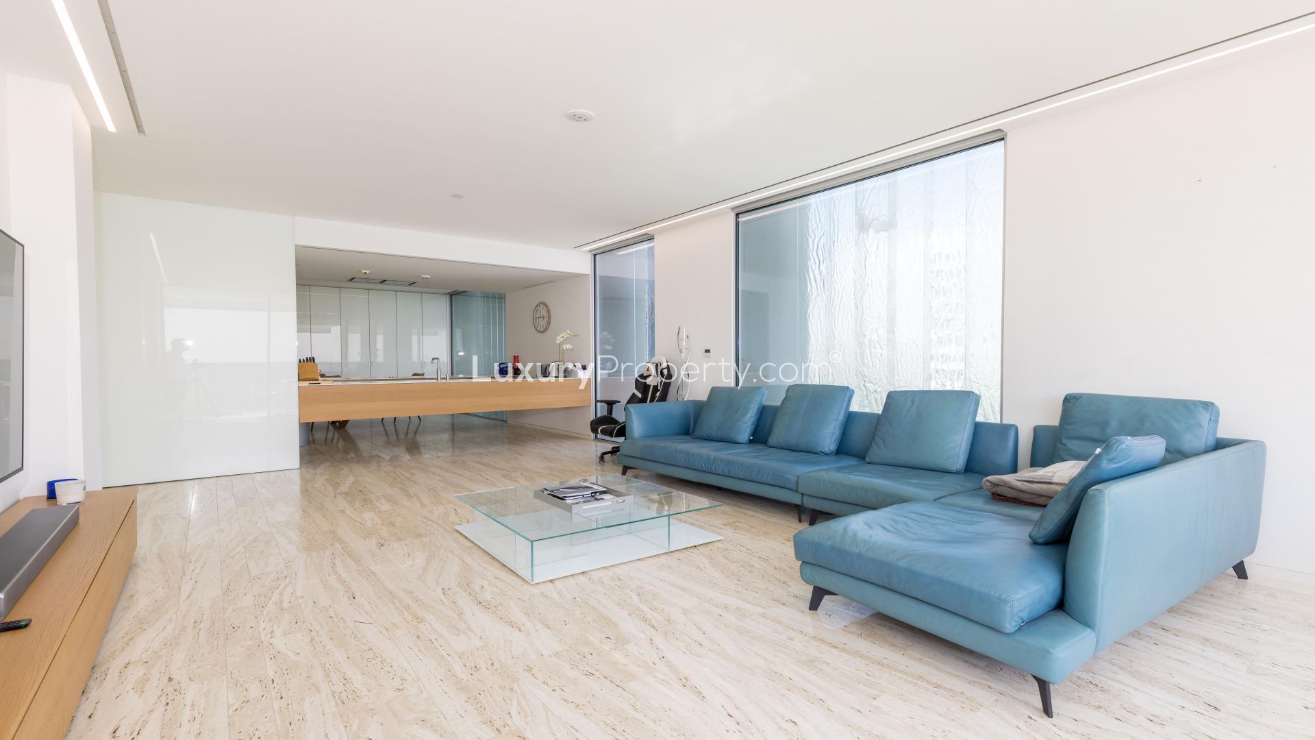 Contemporary furnished living room in Palm Jumeirah apartment with blue sofa and glass table