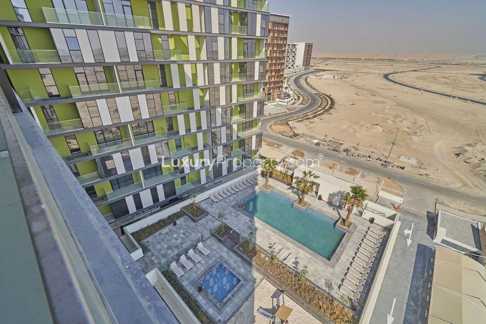 "Balcony view of modern apartment in The Pulse Boulevard, Dubai South, for sale.",Modern apartment building with pool view in The Pulse Boulevard, Dubai South