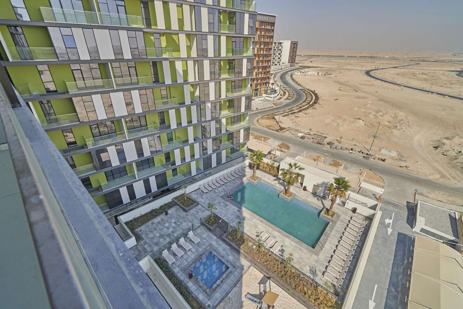 "Balcony view of modern apartment in The Pulse Boulevard, Dubai South, for sale.",Modern apartment building with pool view in The Pulse Boulevard, Dubai South