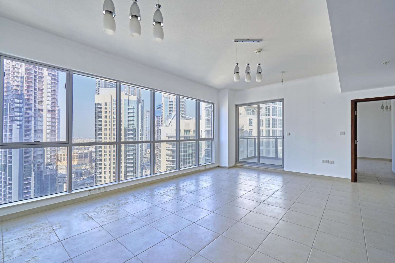 Empty Downtown Dubai apartment with Burj Khalifa view through large window, tiled floors