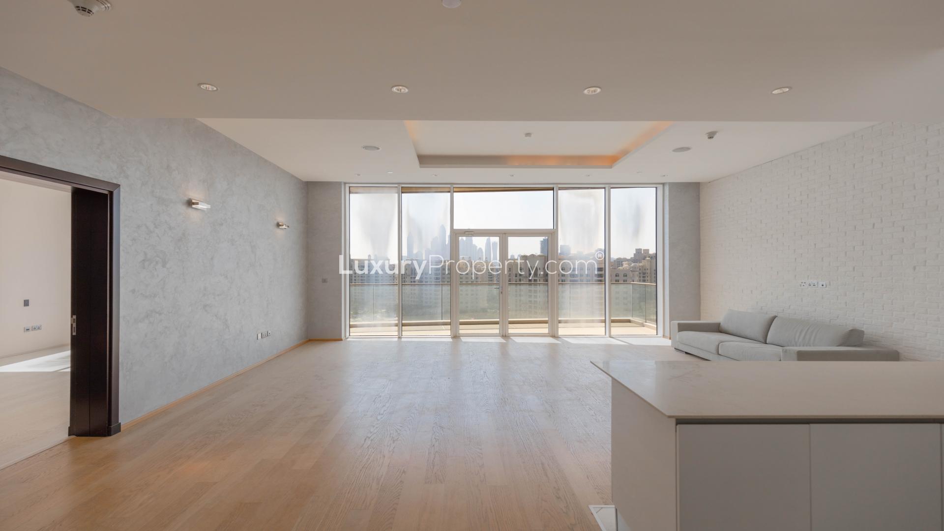 "High-floor apartment view of Tiara Residences beach, Palm Jumeirah, Dubai skyline in background.",Renovated high-floor apartment living room with balcony in Tiara Residences, Palm Jumeirah