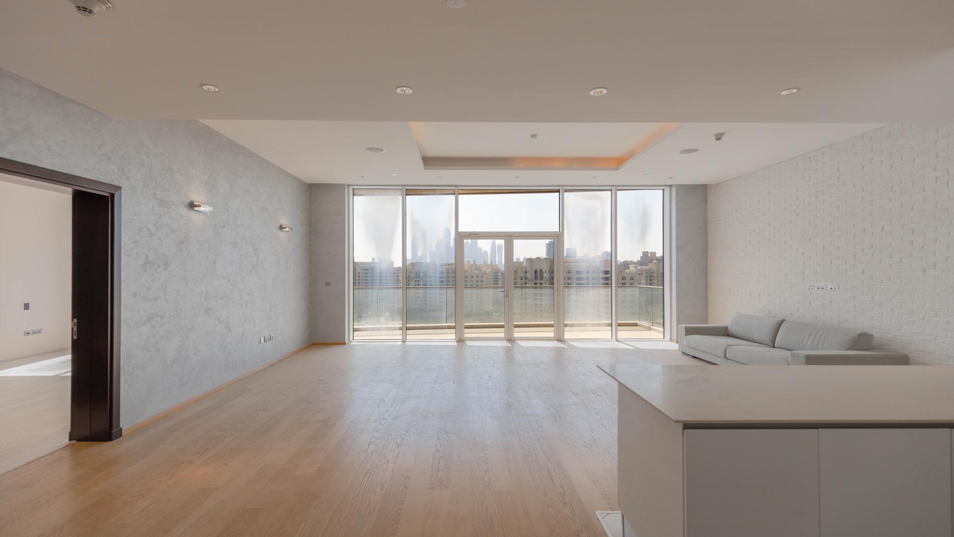 "High-floor apartment view of Tiara Residences beach, Palm Jumeirah, Dubai skyline in background.",Renovated high-floor apartment living room with balcony in Tiara Residences, Palm Jumeirah