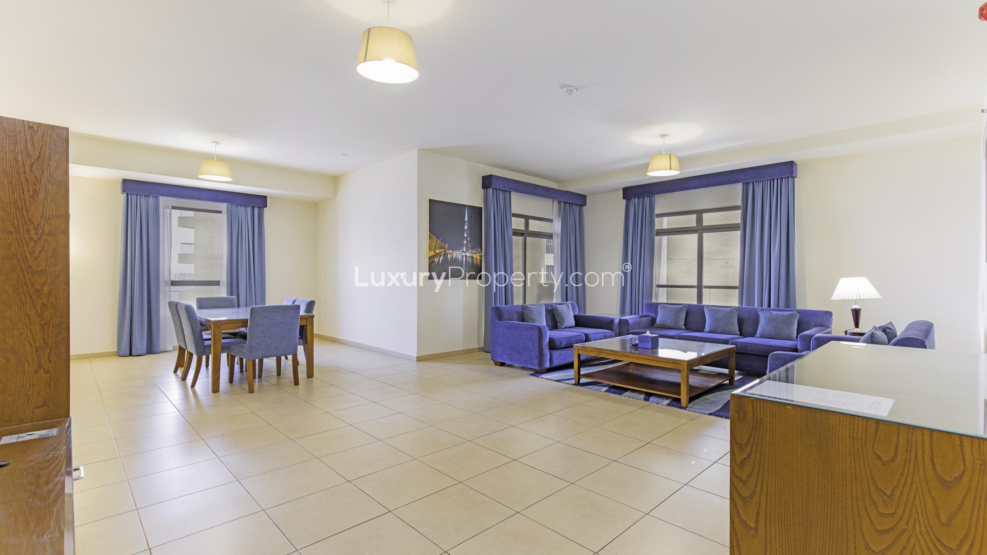 Spacious living room in Jumeirah Beach Residence apartment, featuring blue sofas and dining area