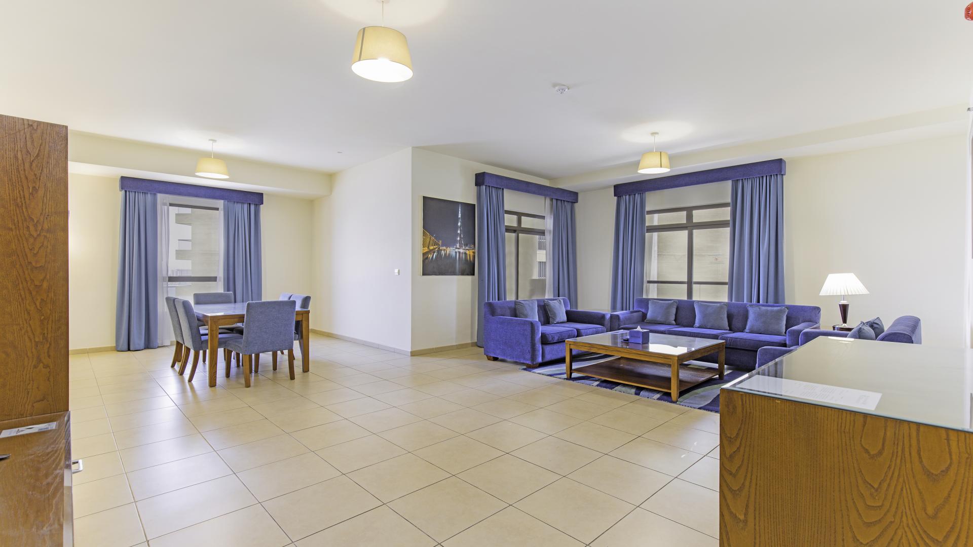 Spacious living room in Jumeirah Beach Residence apartment, featuring blue sofas and dining area
