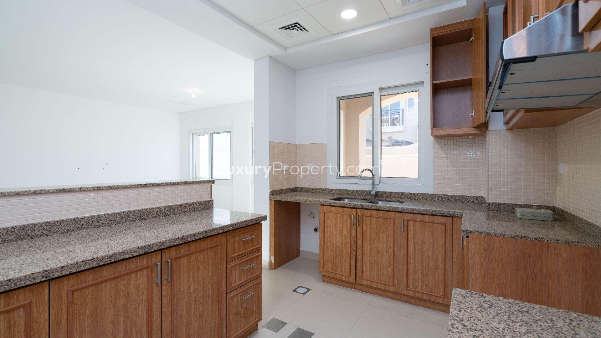 Modern kitchen with wooden cabinets in Bella Casa townhouse, Serena, Dubai for rent