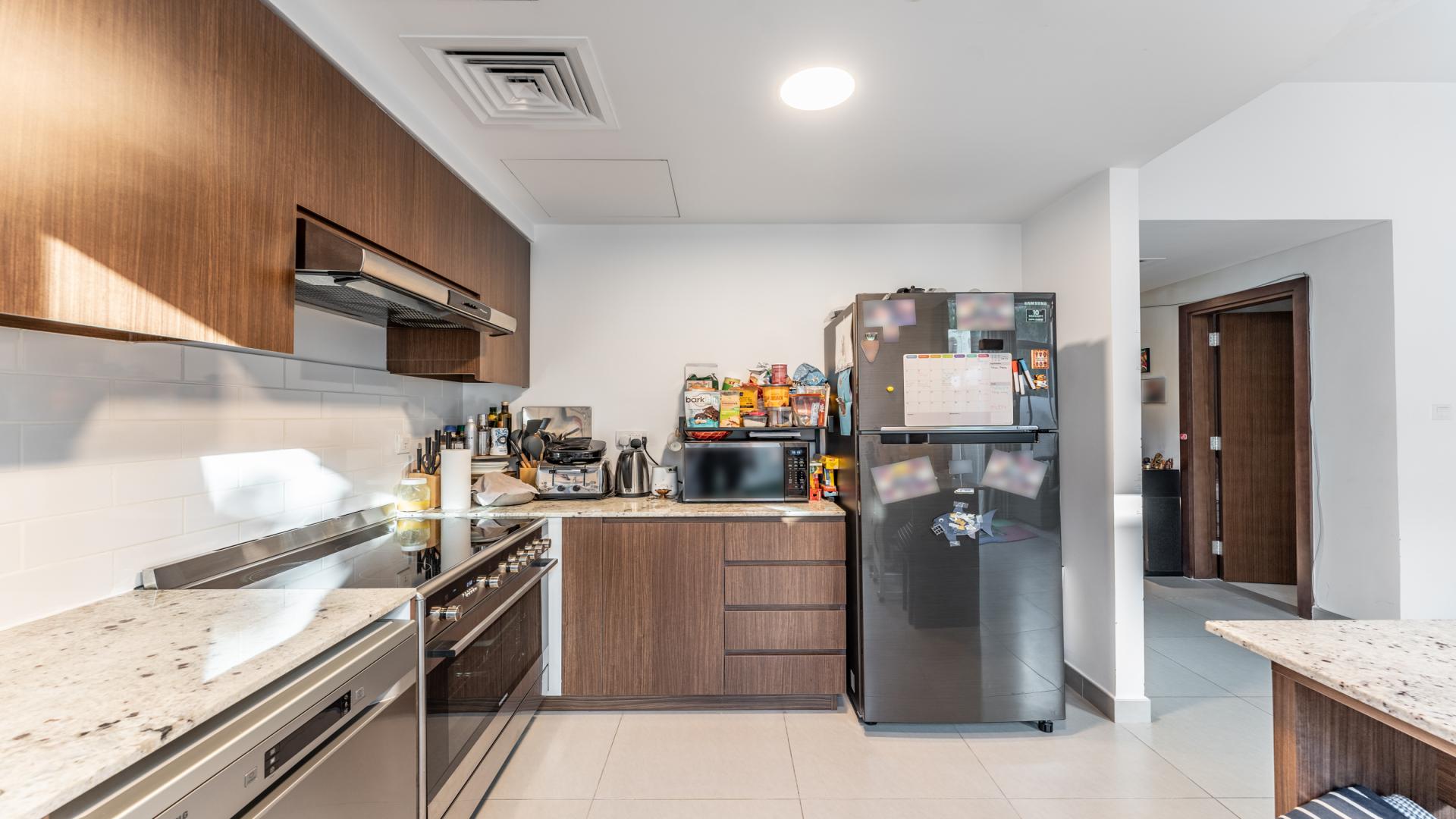 Modern kitchen in luxury Mudon Arabella townhouse with wooden cabinets and stainless steel appliances