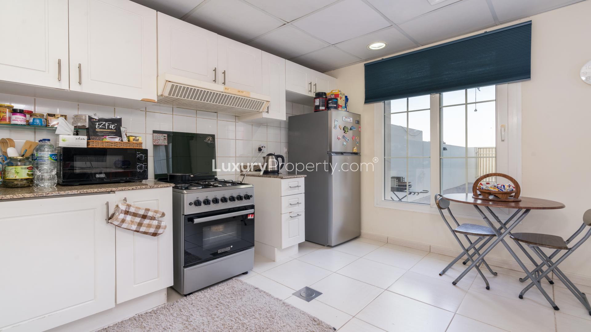 "Modern kitchen in 2-bedroom villa for sale, The Springs, with dining area and appliances.",Modern kitchen in 2-bedroom villa for sale, The Springs community, featuring dining area