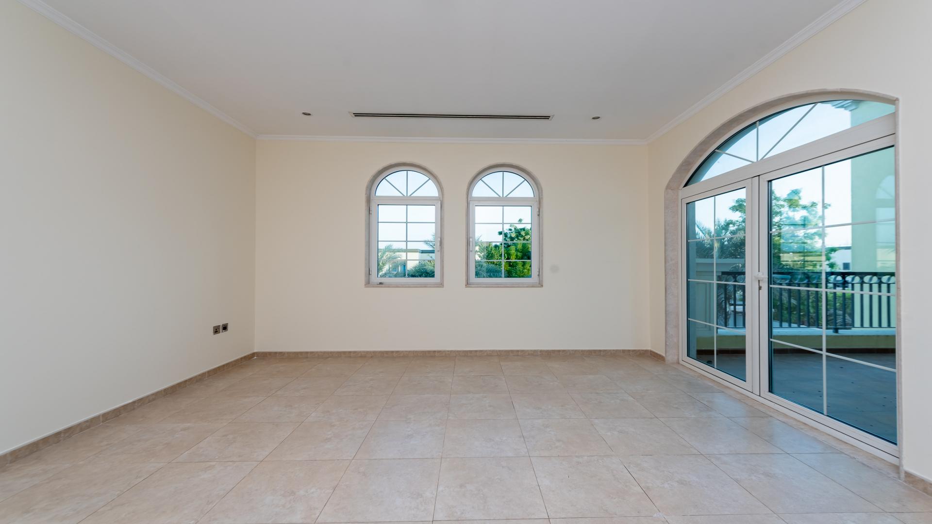 Spacious living room in Jumeirah Park Legacy Villa with arched windows and tiled flooring