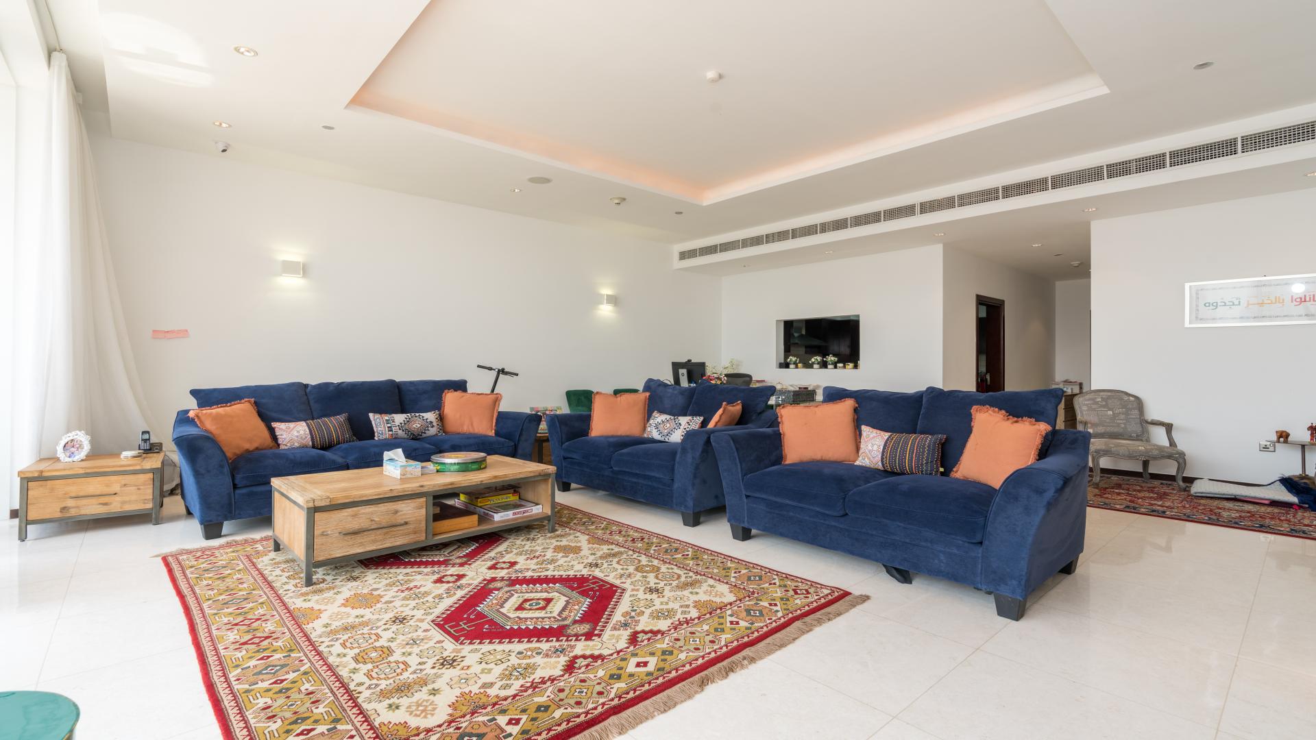 Luxurious living room in Palm Jumeirah apartment, blue sofas, colorful rug, modern decor