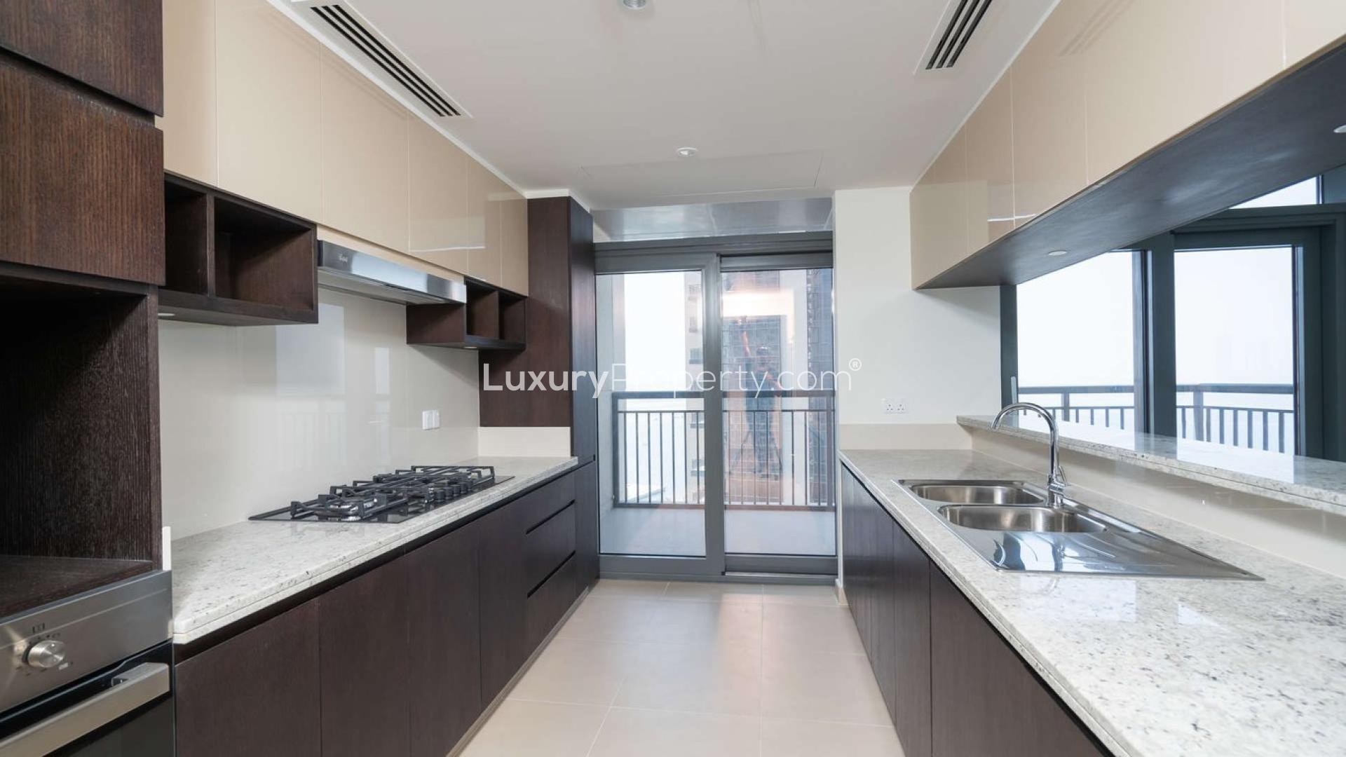 Modern kitchen in 3-bedroom apartment, Dubai Creek Harbour, featuring sleek countertops and balcony view