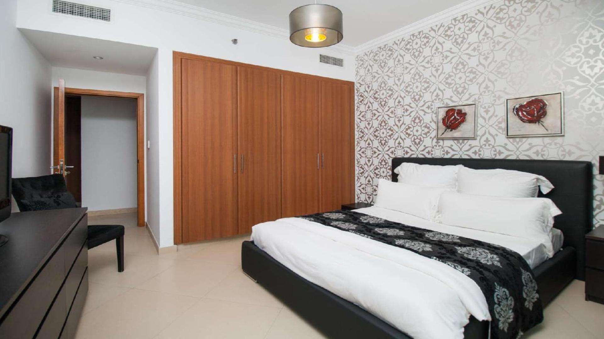 Stylish living room in Dorra Bay apartment, Dubai Marina, with red sofas and patterned walls