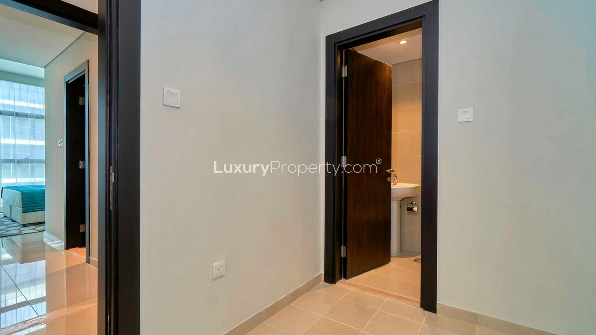 Elegant living room with modern furniture in Damac Hills apartment, large windows, stylish lighting