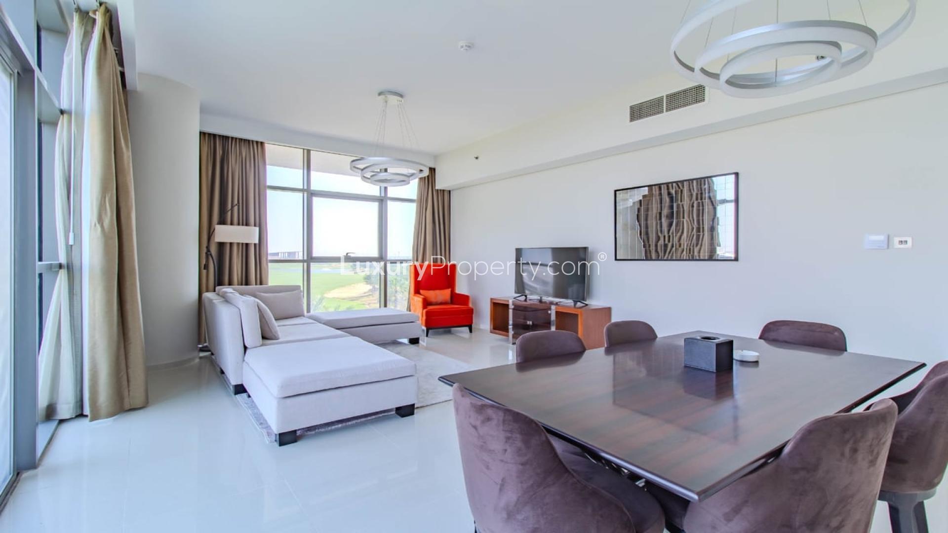 Furnished living and dining area with golf course view in Damac Hills apartment