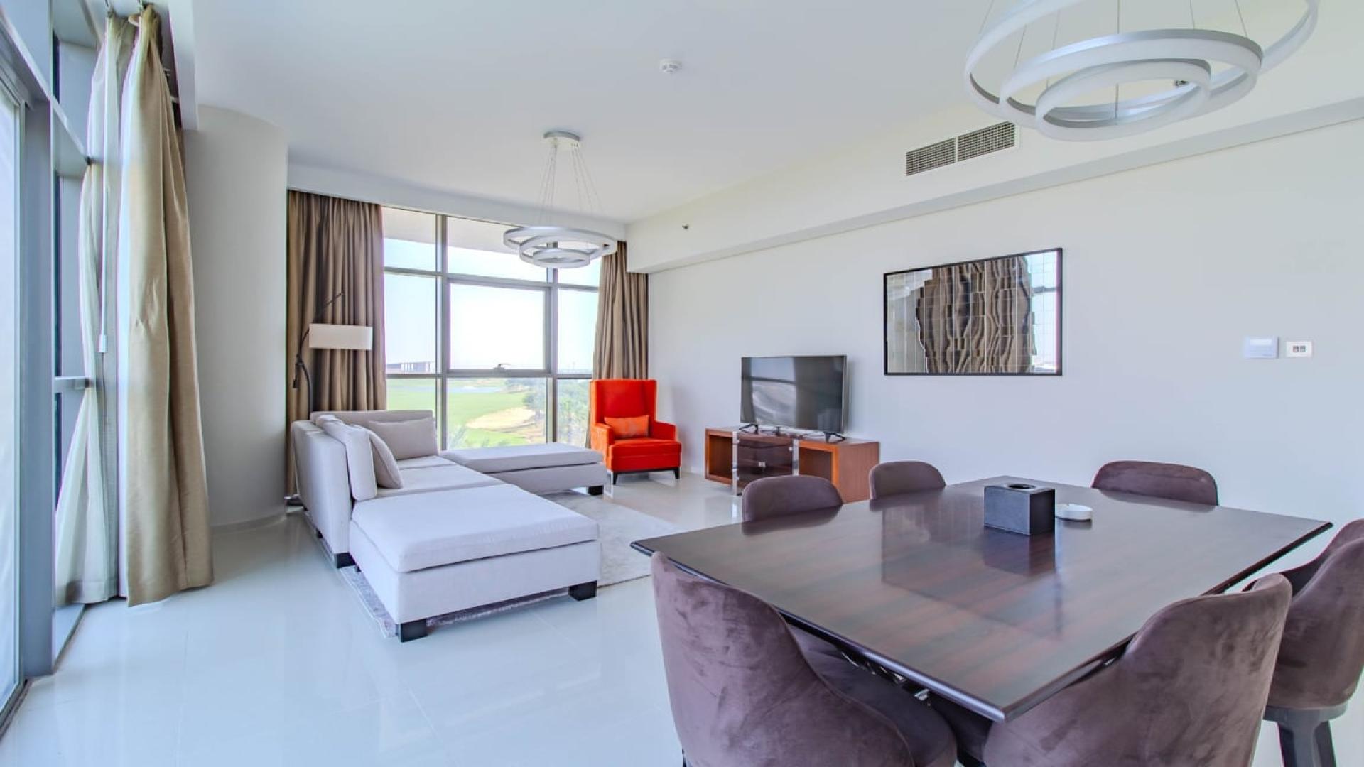 Furnished living and dining area with golf course view in Damac Hills apartment