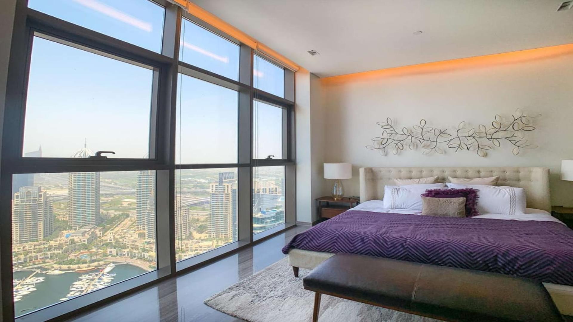 Luxurious bedroom with stunning Dubai Marina views, featuring large windows and modern decor