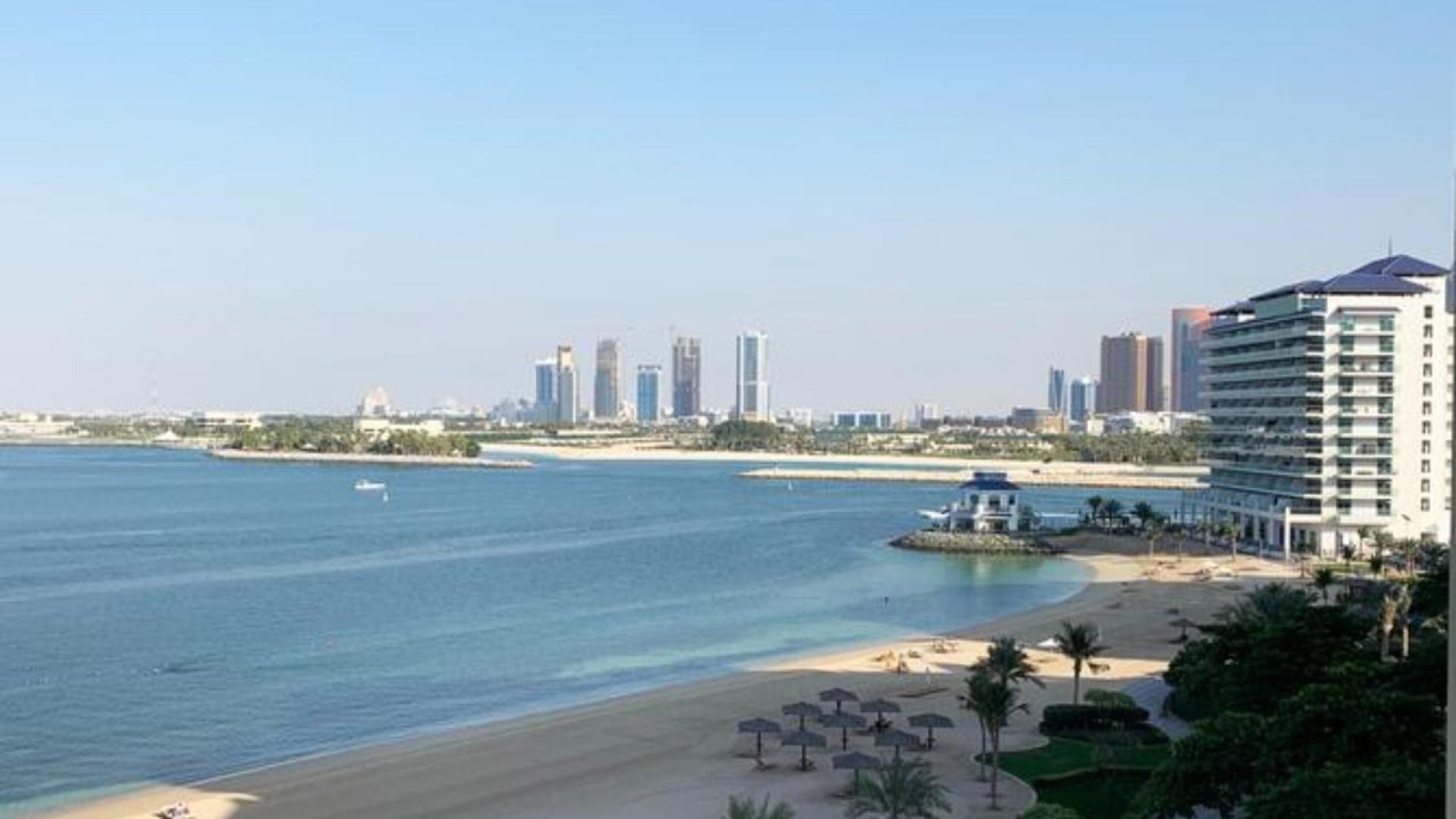 Modern dining area in 3-bed Shoreline Apartment, Palm Jumeirah, with open kitchen and artwork