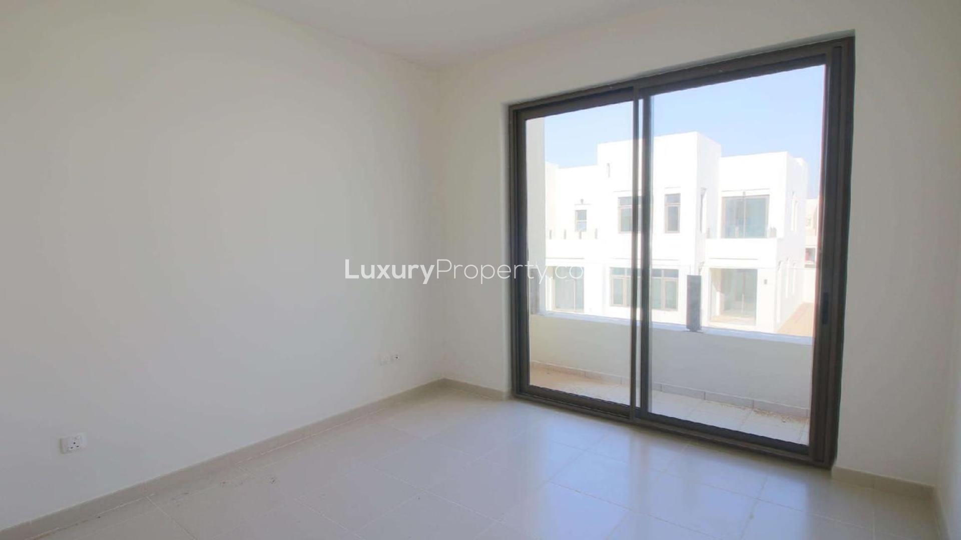 Bright living area in 3-bedroom villa, Mira Oasis, Dubai, with large windows and kitchen view