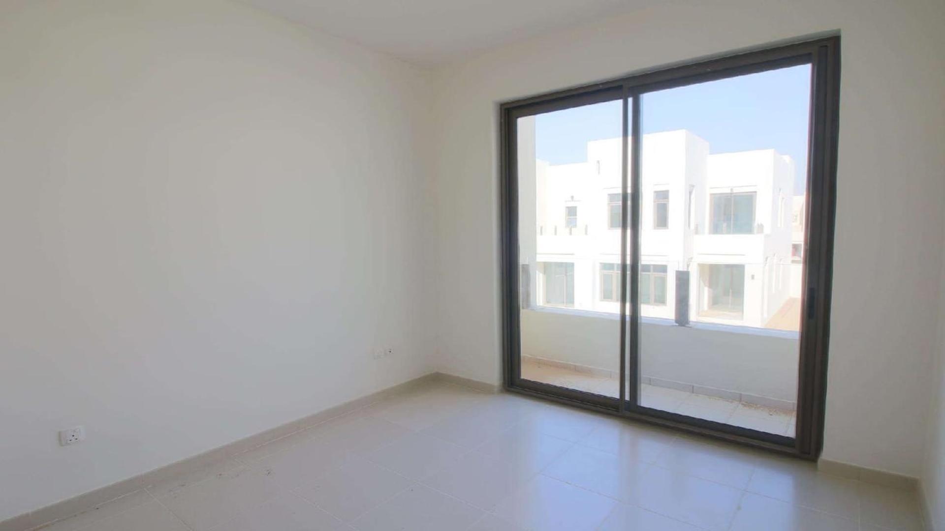 Bright living area in 3-bedroom villa, Mira Oasis, Dubai, with large windows and kitchen view