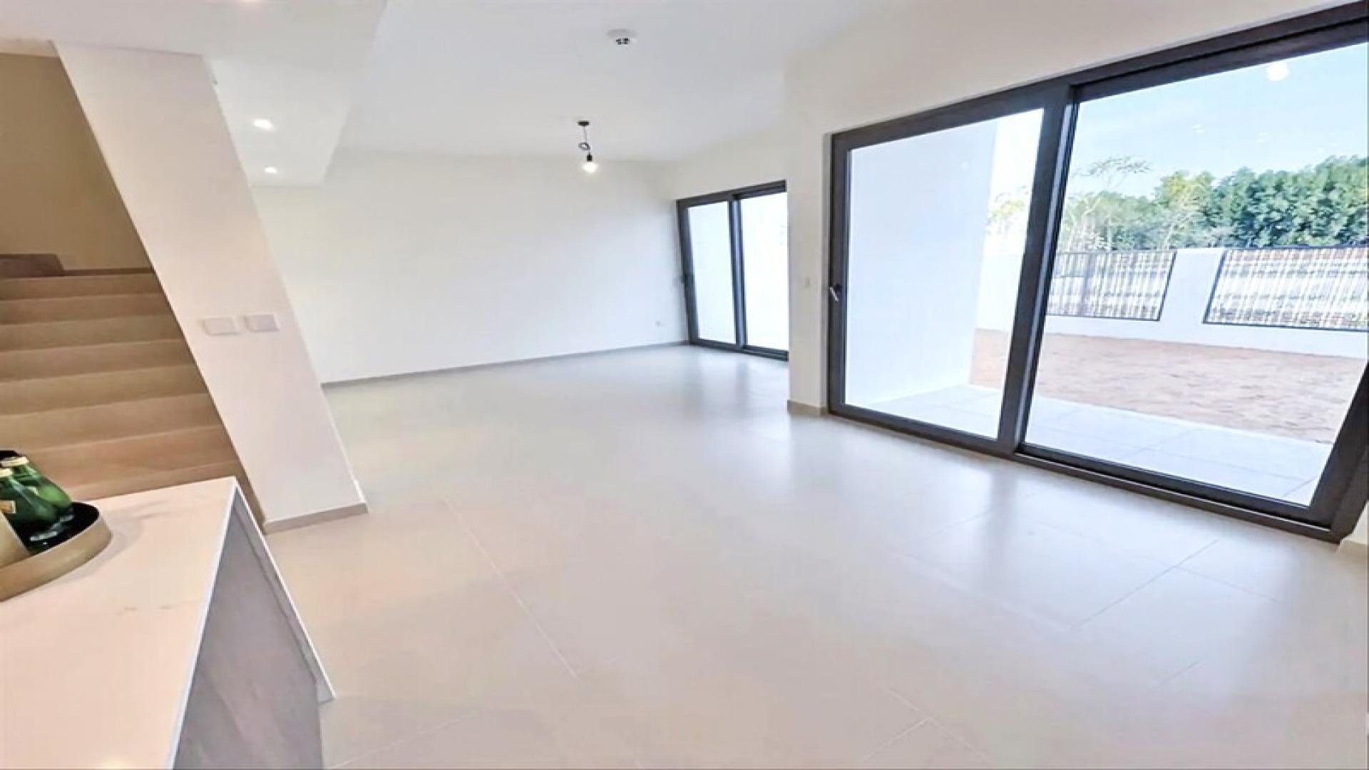 Bright living room in Elan townhouse, Tilal Al Ghaf, with large windows and patio view