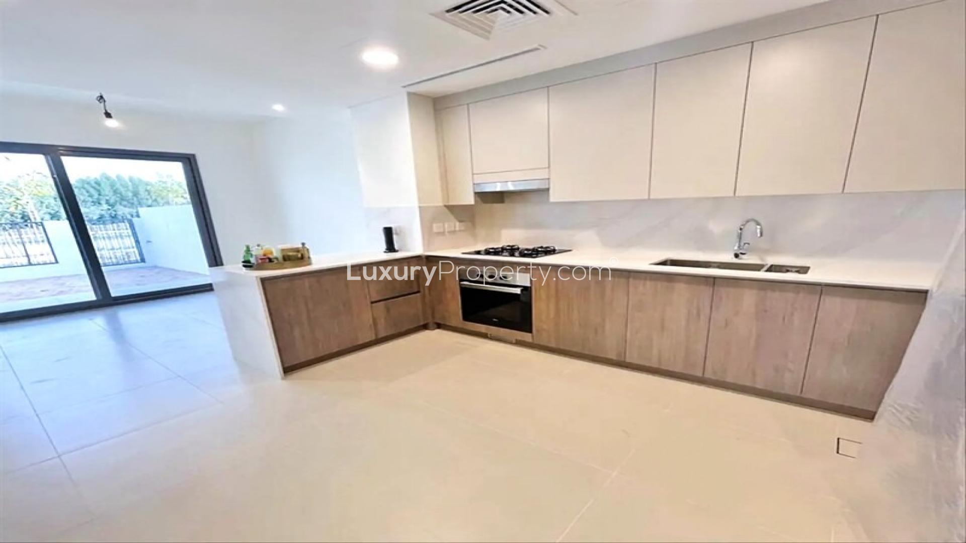 "Spacious living area with large windows in Elan townhouse, Tilal Al Ghaf community.",Modern kitchen in Elan townhouse, Tilal Al Ghaf, featuring sleek cabinetry and spacious layout