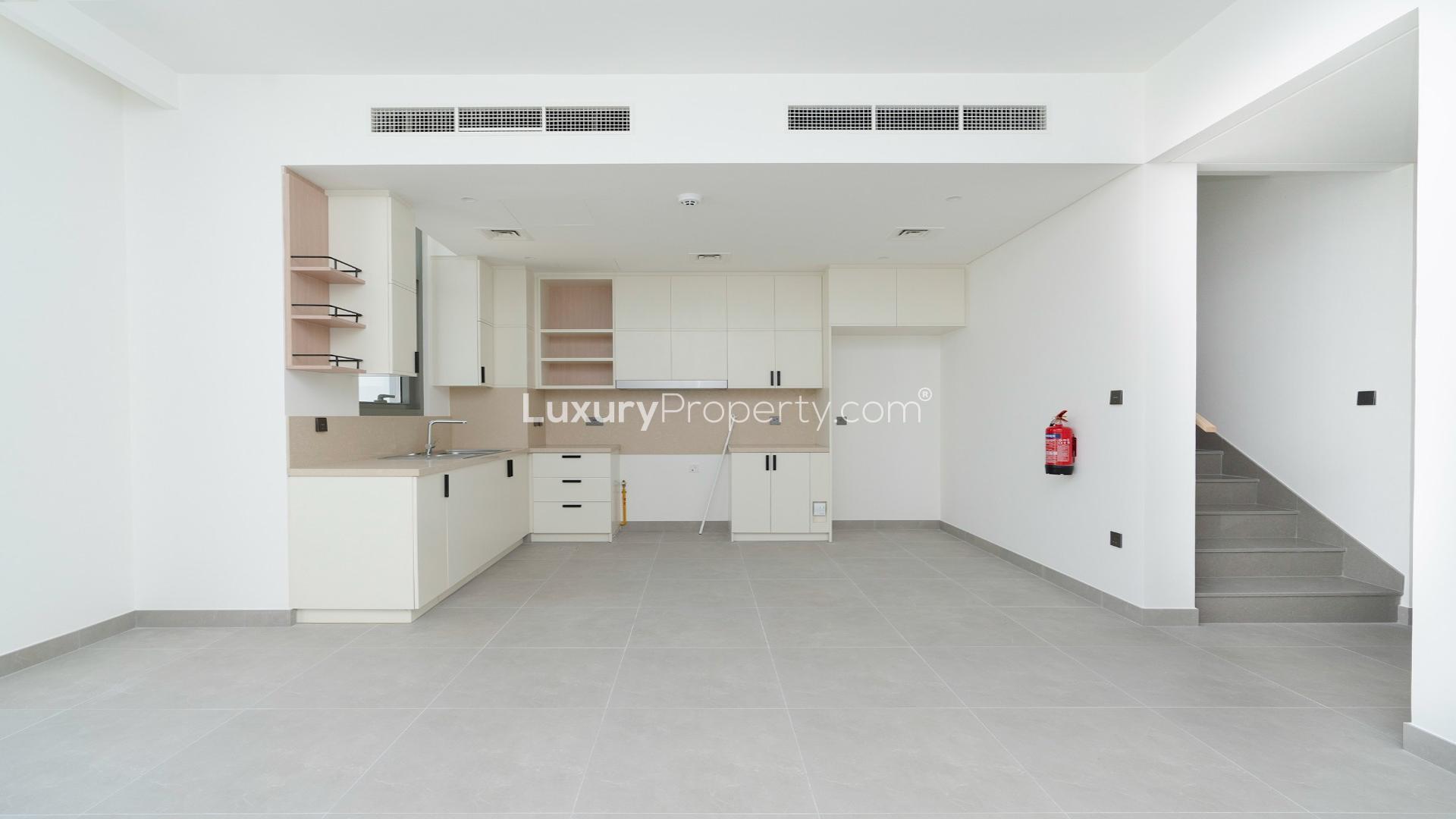 Modern kitchen in Arabian Ranches 3 townhouse, featuring sleek cabinetry and large windows
