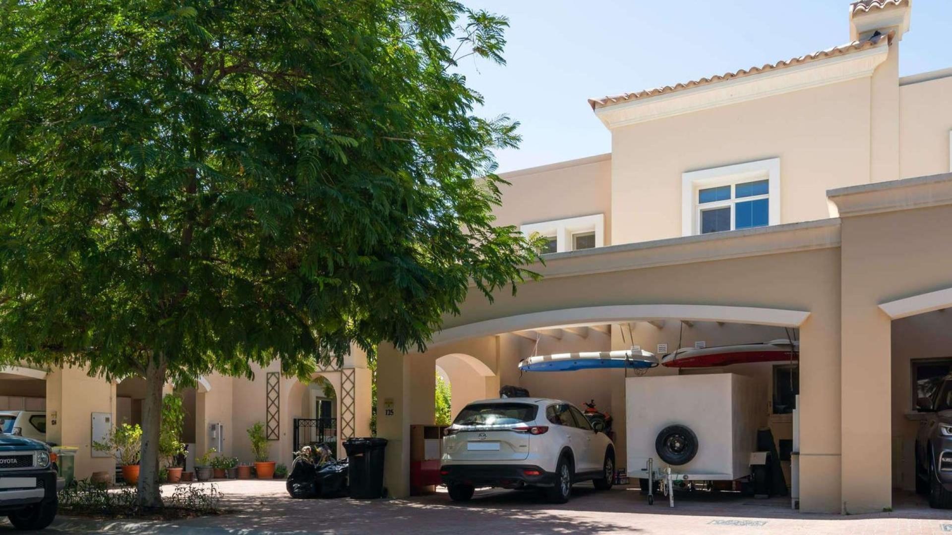 "Front view of spacious 3-bedroom villa in Alma, Arabian Ranches with carport and trees.",Kitchen in 3-bedroom Type 2E villa, Alma, Arabian Ranches, featuring modern appliances and island