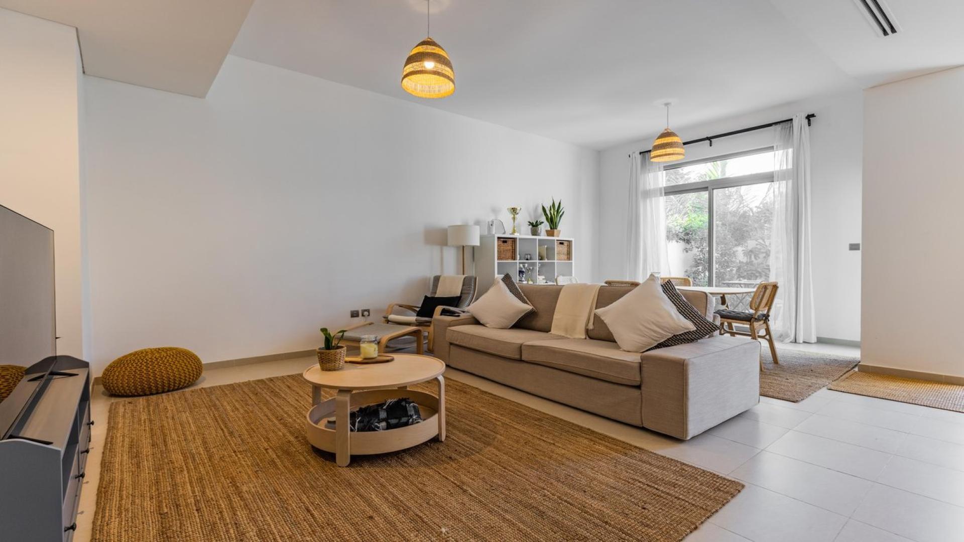 Modern townhouse exterior in Reem Community, Arabian Ranches 2, featuring spacious carport and greenery