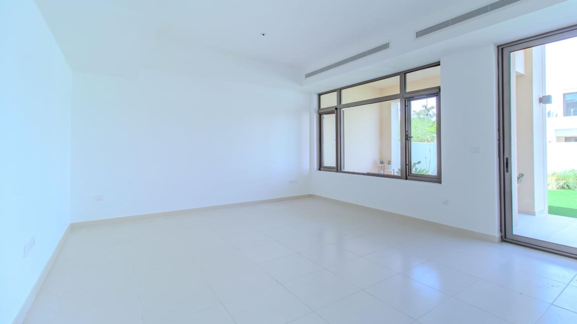 "Spacious Mira Oasis townhouse with lush garden and patio, Reem community, available for rent.",Empty living room with large windows in Mira Oasis townhouse, Reem community, available for rent