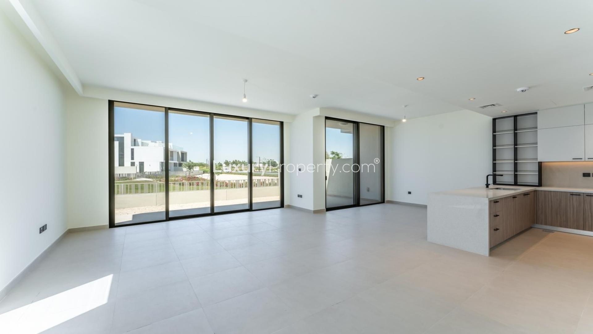 Open-plan living area with large windows and modern kitchen in Golf Grove villa, Dubai Hills